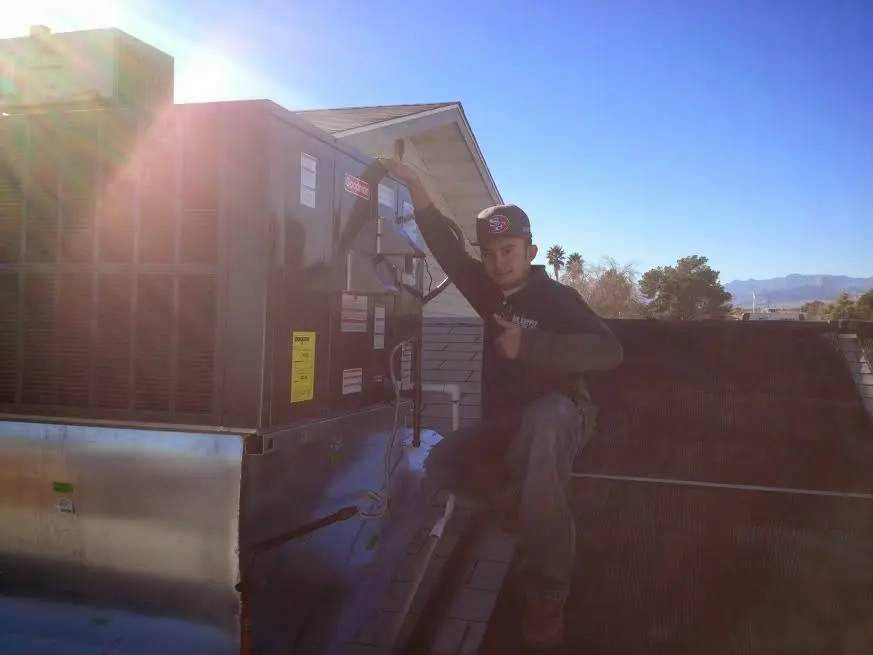 HVAC technician performing AC Tune-Up on a rooftop unit in Oceanside